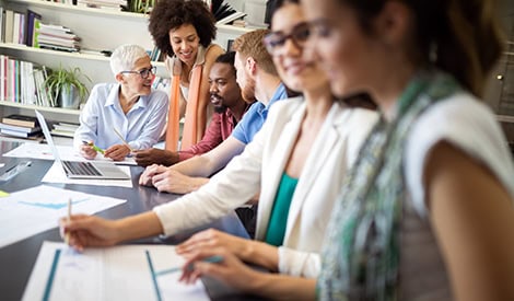 Groupe de professionnels en réunion de travail dans un bureau moderne, illustrant la collaboration, le travail d'équipe et la diversité en entreprise.